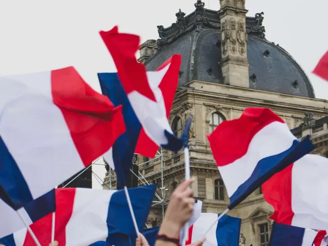 french flag flying in front of old building