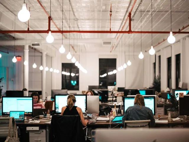 people sitting in front of screens in a computer lab
