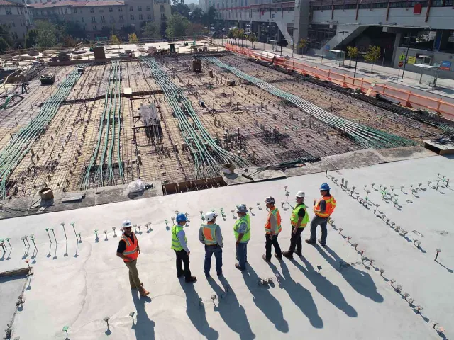 people in helmets and high vis looking out over a large construction site