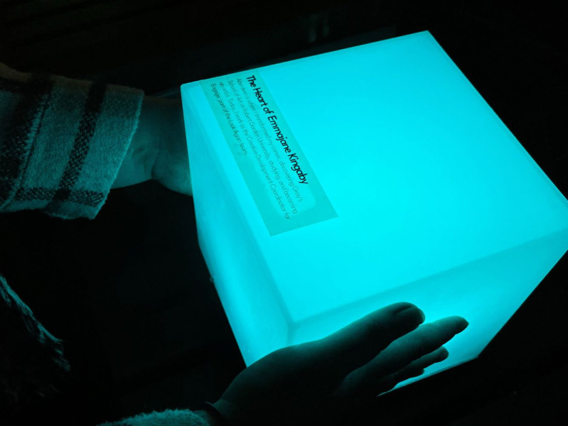 Emmajane's hand touching a glowing cube with her name on it