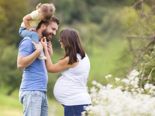 Image shows man with child on his shoulders and expectant mother, from Birth of Brilliance