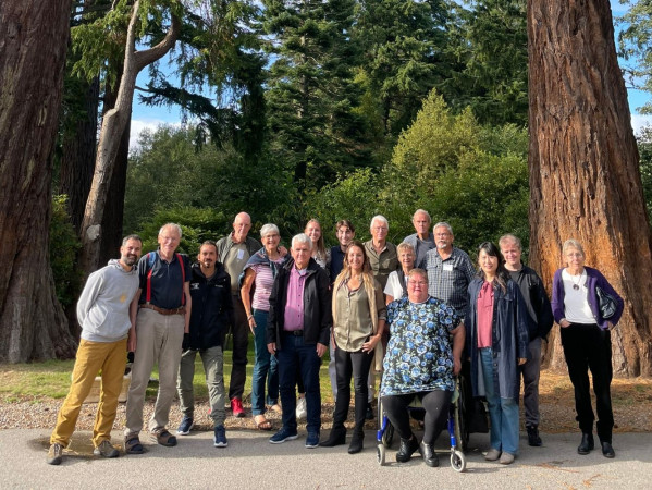 Community members underneath tall trees in a forest