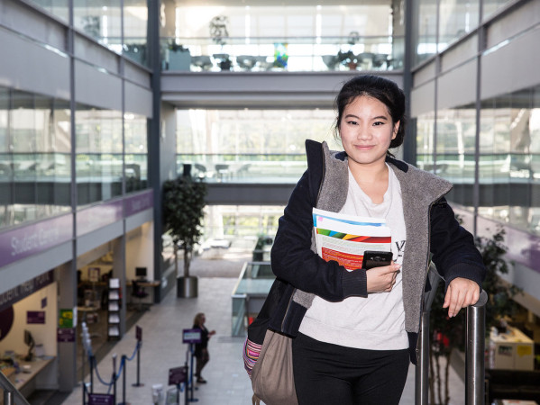 student holding books on campus