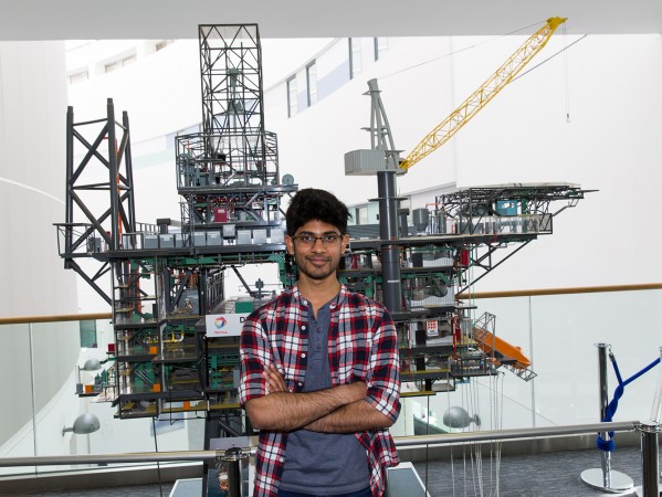student in front of oil rig model student in front of oil rig model