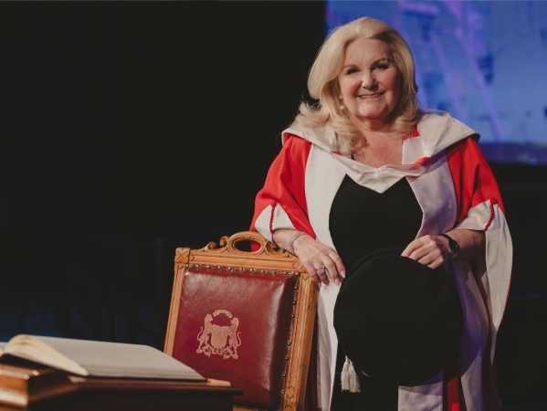 Lynne Smith posing a graduation wearing a red gown