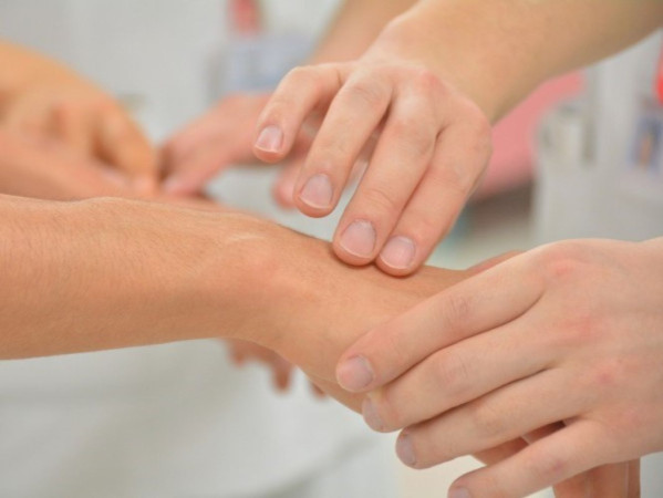 Image shows a nurse taking someone's pulse