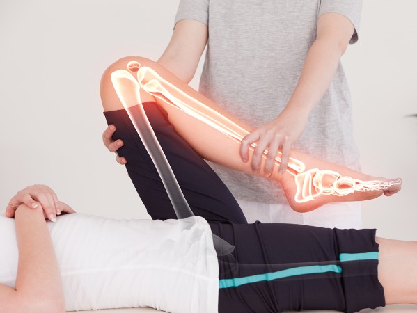 graphic of a bone overlaid on a photo of a physiotherapist moving a patients leg graphic of a bone overlaid on a photo of a physiotherapist moving a patients leg