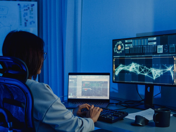 person coding on a desktop computer with multiple screens