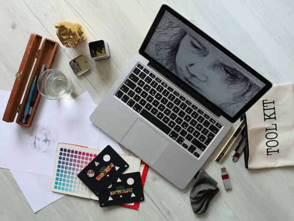 laptop displaying digital art surrounded by art tools