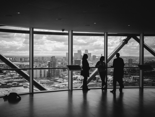 Black and white photo of people at the top of a high rise building looking out of the window
